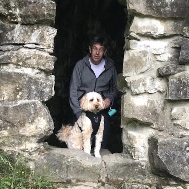 David, our CFO, and his dog Whiskey, an Australian Labradoodle, stood by a stone wall